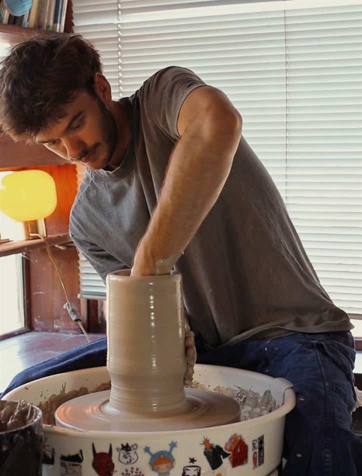 Robin Leloup façonne un vase haut au tour dans son atelier