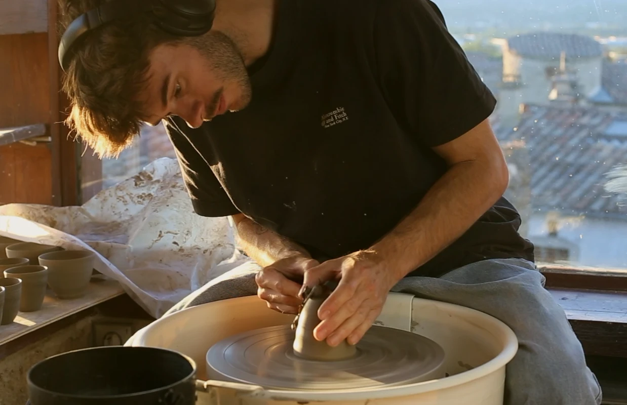 Robin Leloup tourne une pièce au tour de potier, devant la fenêtre de son atelier
